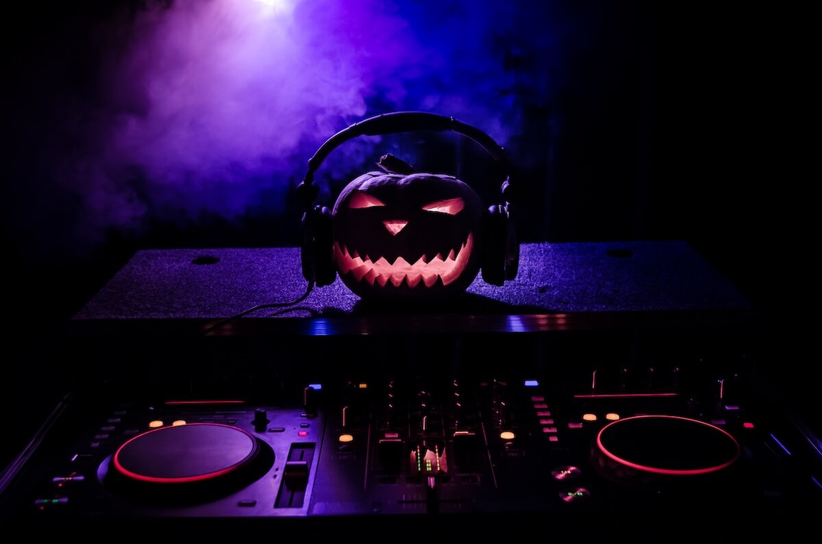 Shutterstock: Halloween pumpkin on a dj table with headphones on dark background with copy space. Happy Halloween festival decorations and music concept