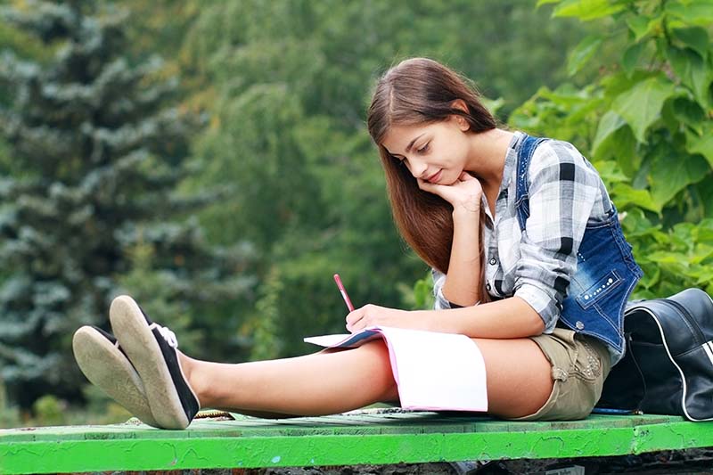 Brown haired girl writing in her school notebook