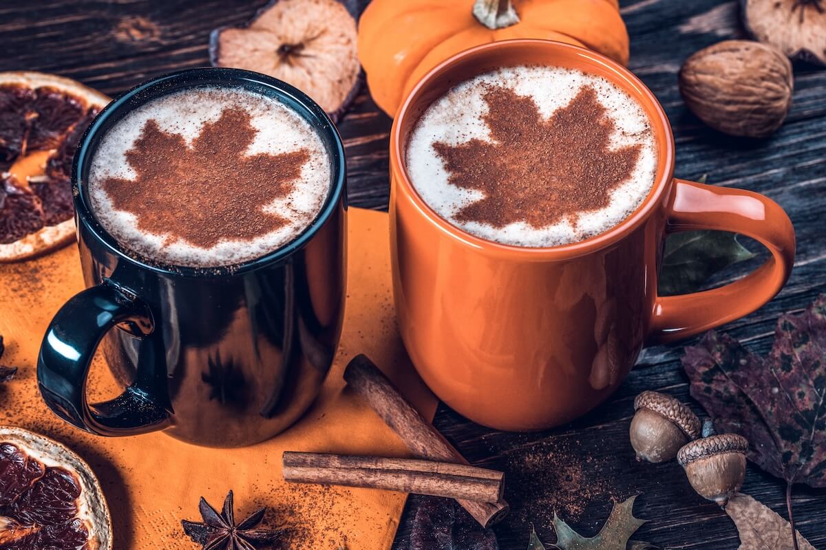 Shutterstock: Maple Spice Latte. Milk foam Decorated Maple leaf. Fall leaves, dried fruits, orange slices, acorns, star anise, pumpkins, apple, cinnamon sticks on wooden board. Autumn season.