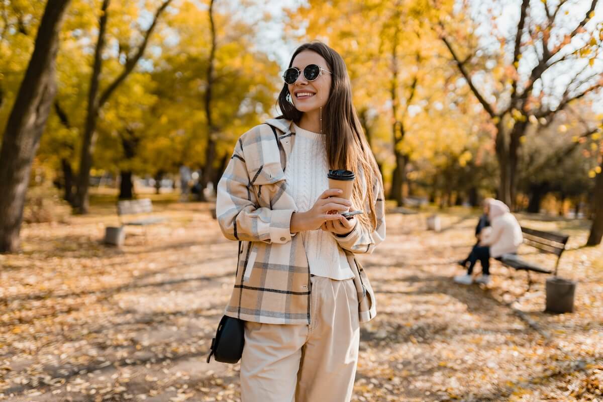 Shutterstock: attractive young woman walking in autumn park with coffee wearing checkered coat, sunglasses, happy mood, fashion style trend