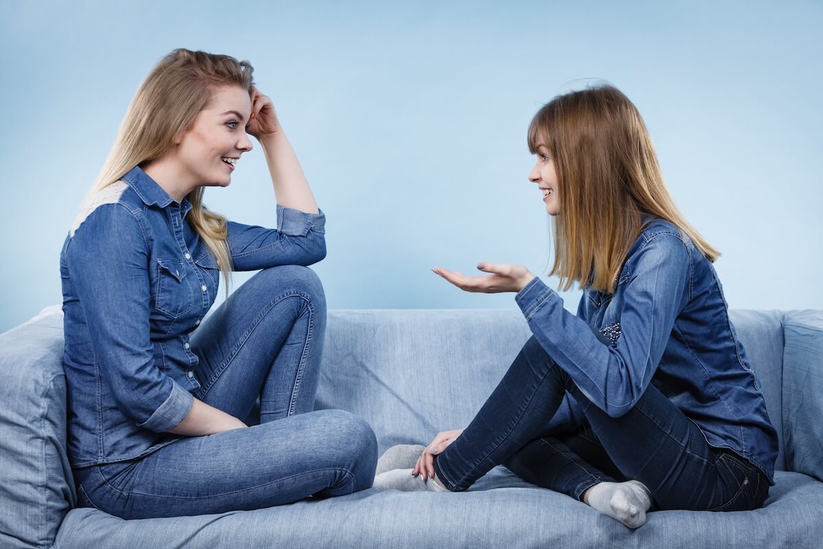 Shutterstock: Friendship, human relations concept. Two happy women friends or sisters wearing jeans shirts having fun conversation.