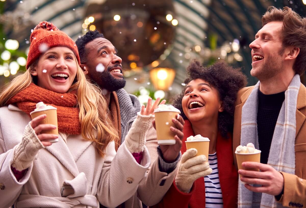 Shutterstock: Group Of Friends Drinking Hot Chocolate With Marshmallows In Snow At Outdoor Christmas Market