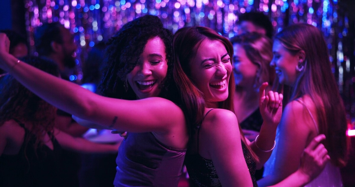 Shutterstock: Dancing, energy and friends in club, night and fun for women, bonding and celebration in weekend or group. Lights, dark and listening to music, smile and people in rave, disco or festival on New Year