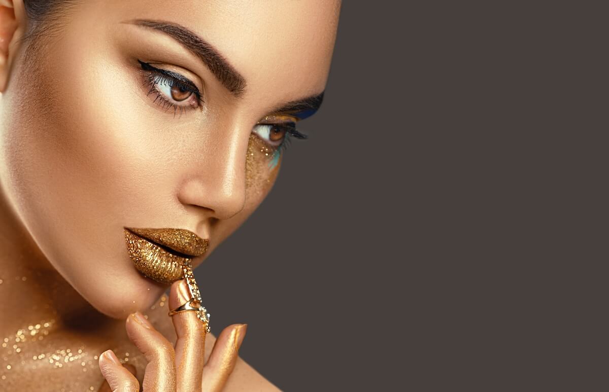 Shutterstock: Fashion art Golden skin Woman face portrait closeup. Beauty gold eyes, Lips and Skin. Model girl. Glamour shiny professional makeup