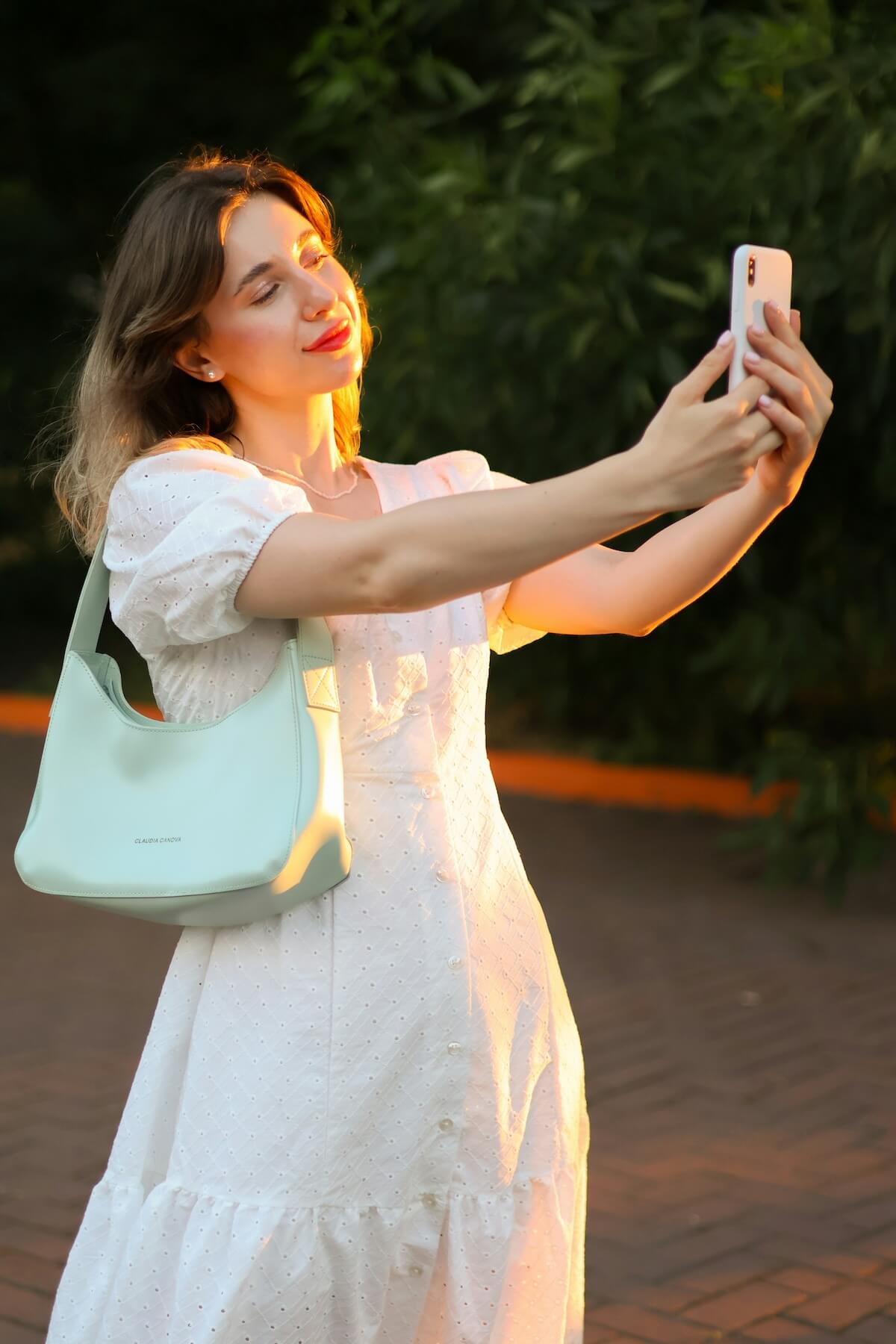 Unsplash: Woman in white taking sunset selfie by Anna Keibalo