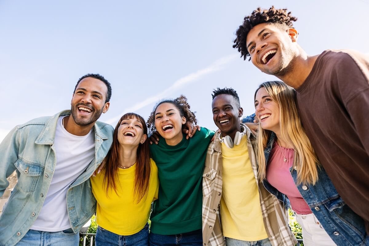 Shutterstock: Young group of people having fun together outdoors in a sunny day. Multiracial best friends bonding enjoying time together at city street. United millennial students laughing.