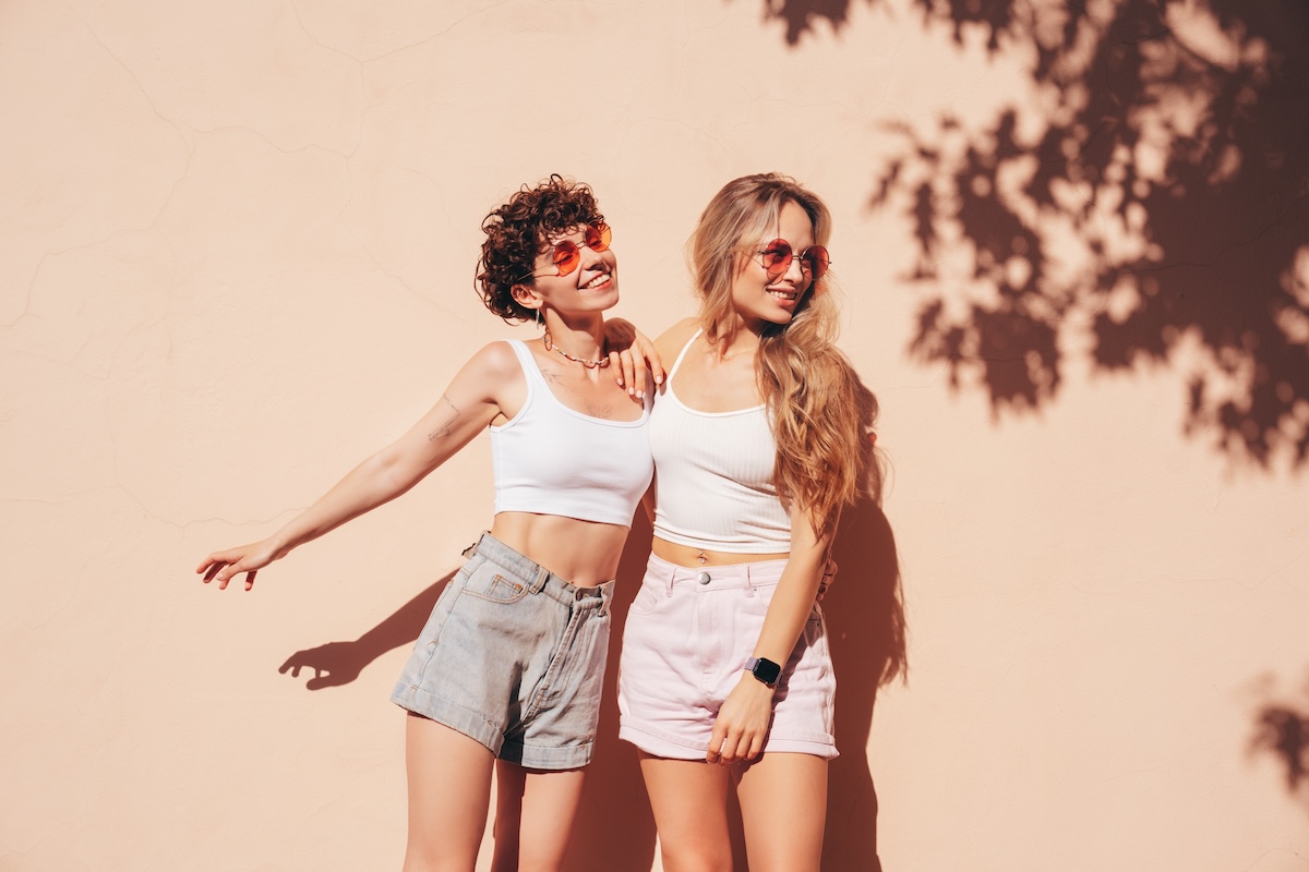Shutterstock: Two young beautiful smiling hipster female in trendy summer white t-shirt and shorts clothes. Sexy carefree women posing in the street. Positive models having fun, hugging and going crazy, near wall