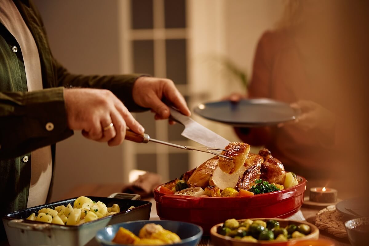 Shutterstock: Cloe up of man carving roast turkey during Thanksgiving dinner in dining room.
