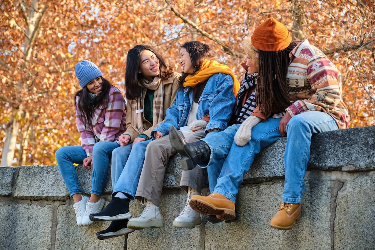 Shutterstock: Happy multi-ethnic group of young hipster diverse student friends having fun while hanging out sitting together outdoors. Friendship concept.