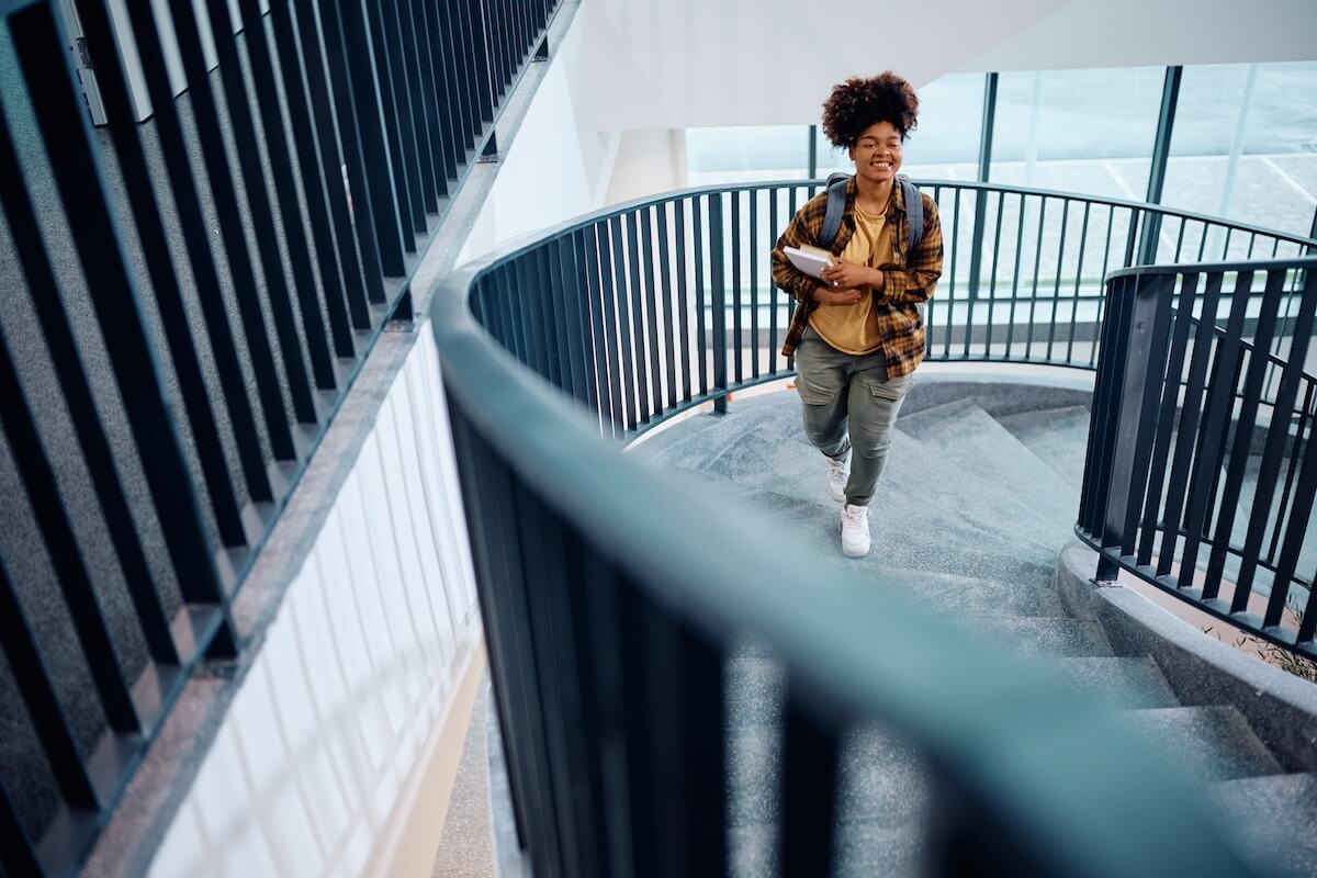 Shutterstock: Happy African American student walking up the stairs at university hallway.