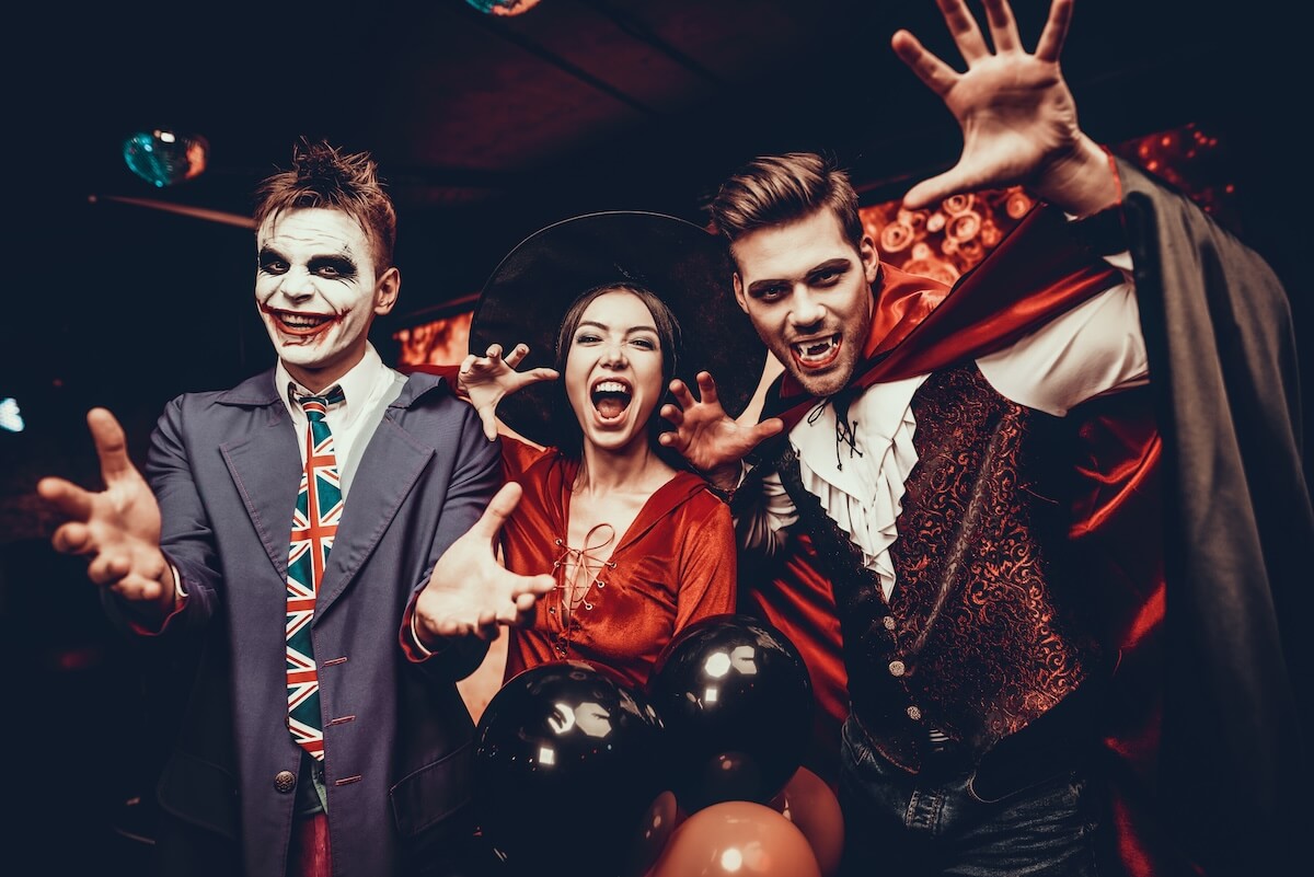 Shutterstock: Young People in Costumes Celebrating Halloween. Group of Young Happy Friends Wearing Halloween Costumes having Fun at Party in Nightclub by doing Scary faces. Celebration of Halloween