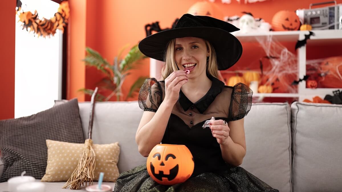 Shutterstock: Young blonde woman having halloween party eating candy sweet at home