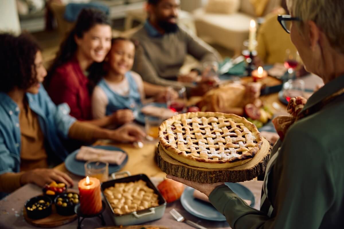 Shutterstock: Close up of senior woman serving traditional sweet pie during family meal on Thanksgiving.