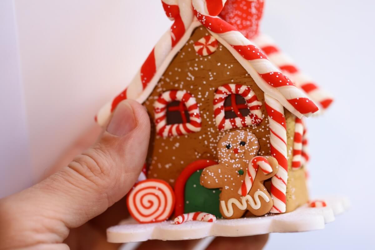 Shutterstock: A person holding a festive gingerbread house decorated with candy canes, perfect for holiday celebrations or winter-themed designs.