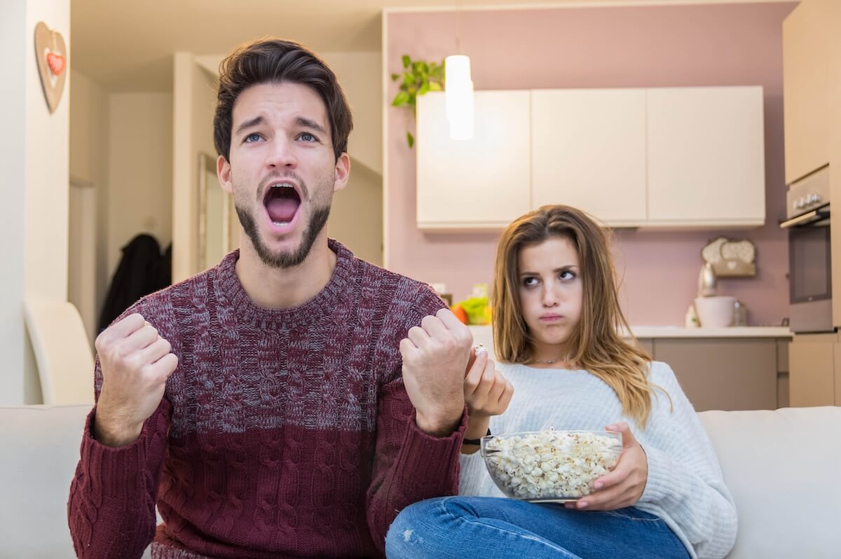 Shutterstock: Bored girl watching the football game with her boyfriend