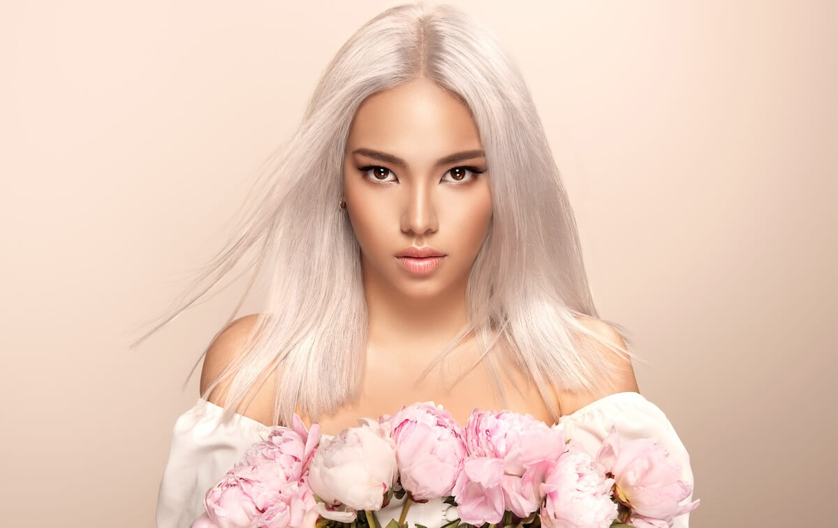 Shutterstock: Beautiful asian woman with hair coloring in ultra blond and flowers. Stylish hairstyle done in a beauty salon. Fashion, cosmetics and makeup