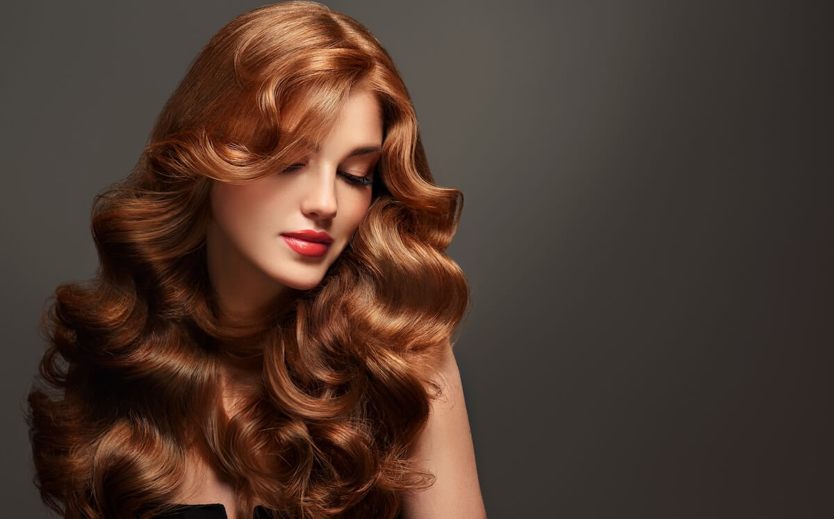 Shutterstock: Beautiful model girl with long curly red hair . Smiling woman hairstyle wavy curls . Fashion , beauty and makeup portrait. Treatment, care and spa procedures.