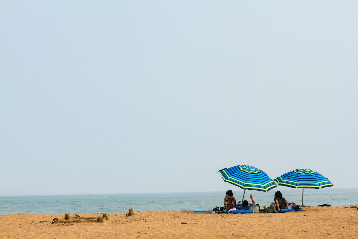Unsplash: Vacationers on beach under umbrellas by John McArthur