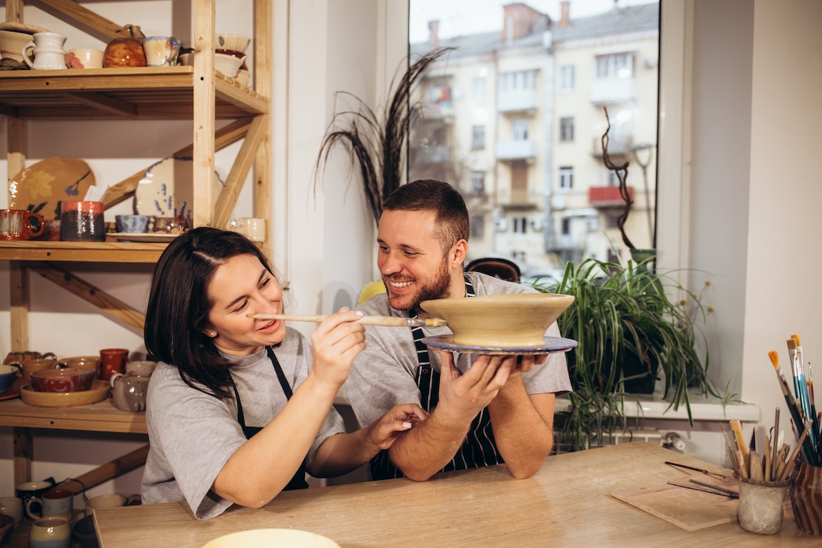 Shutterstock: adult couple smiling while doing creative painting on bowls in pottery workshop.
