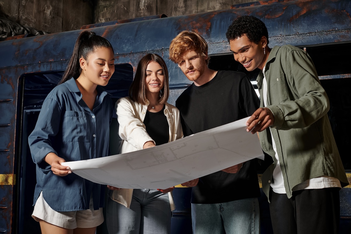Shutterstock: group of happy young multicultural friends solving quest task while looking at map in escape room