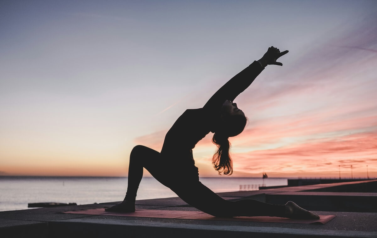Unsplash: Woman doing yoga pose against suneset by Kike Vega