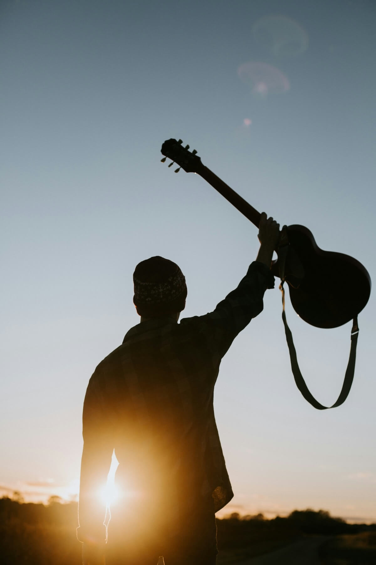 Unsplash: Man with guitar against sunset by Jacob Bentzinger