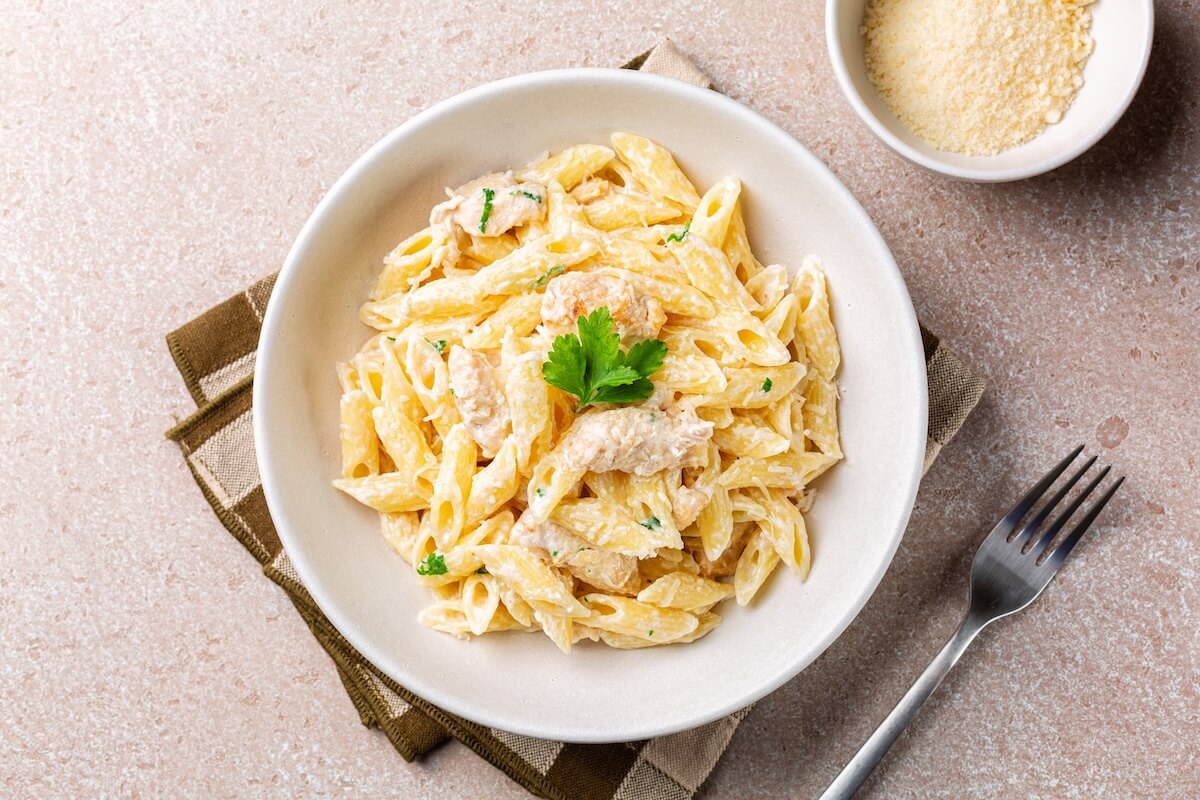 Shutterstock: Chicken Alfredo penne, creamy pasta wich parmesan cheese in a white plate. Directly above.