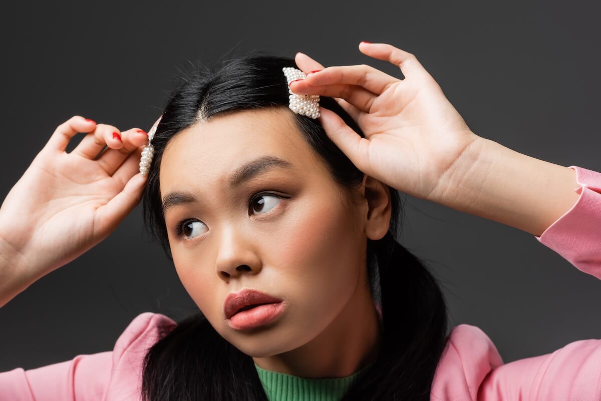 Shutterstock: Pretty asian model touching barrettes and looking away isolated on grey