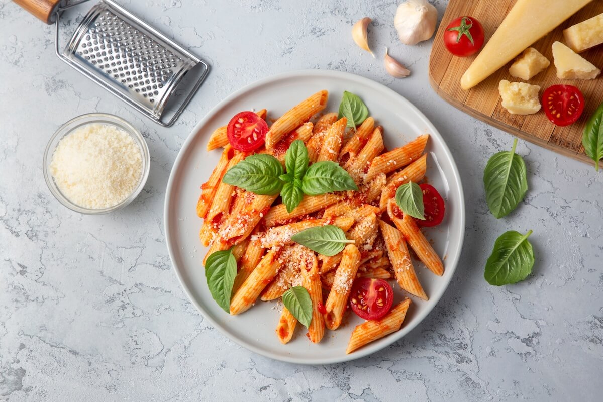 Shutterstock: Classic italian pasta penne alla arrabiata with basil and freshly grated parmesan cheese on dark table. Penne pasta with chili sauce arrabbiata.