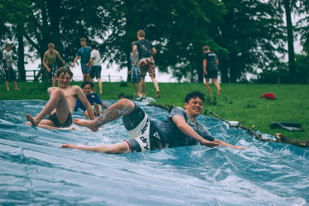 Unsplash: Friends sliding down slip n slide by luke porter