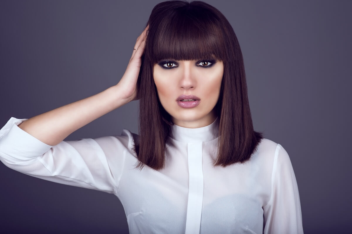 Shutterstock: Portrait of gorgeous young dark-haired woman with provocative make up and expressive eyes looking straight and touching hair with her hand. Close up. Studio shot.