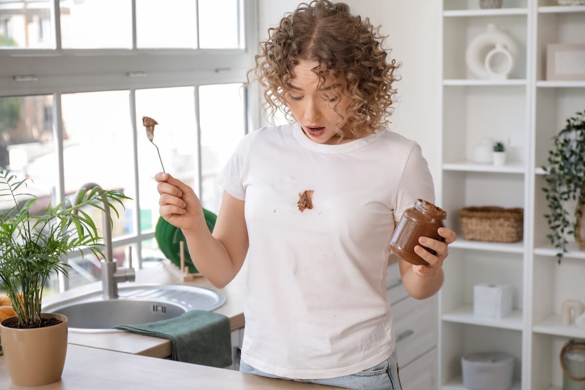 Shutterstock: Young woman stained her t-shirt with chocolate paste in kitchen