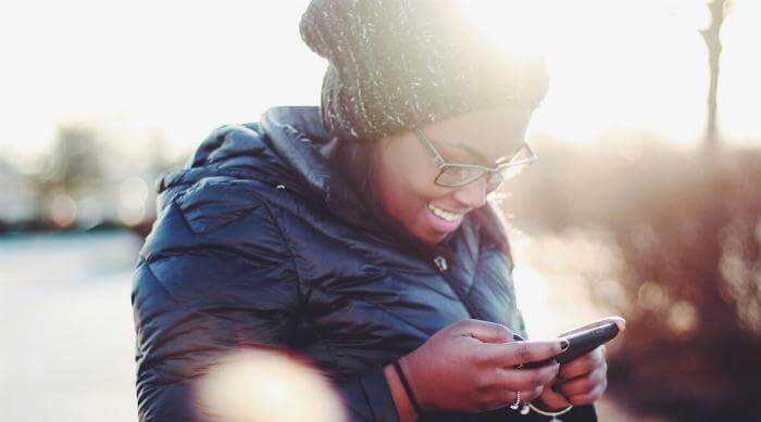 Unsplash: Woman smiling and texting looking at phone