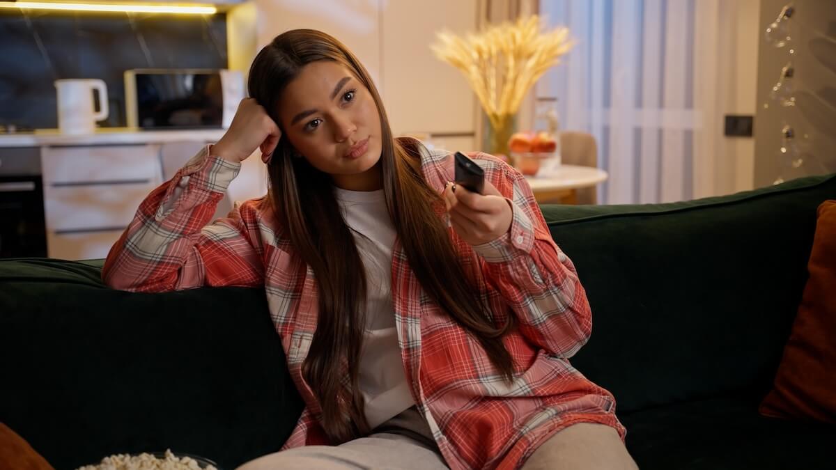 Shutterstock: Bored tired upset girl Caucasian woman alone watching television at home evening night insomnia lazy female teenager on couch relax rest switching TV channels watch boring movie film in living room