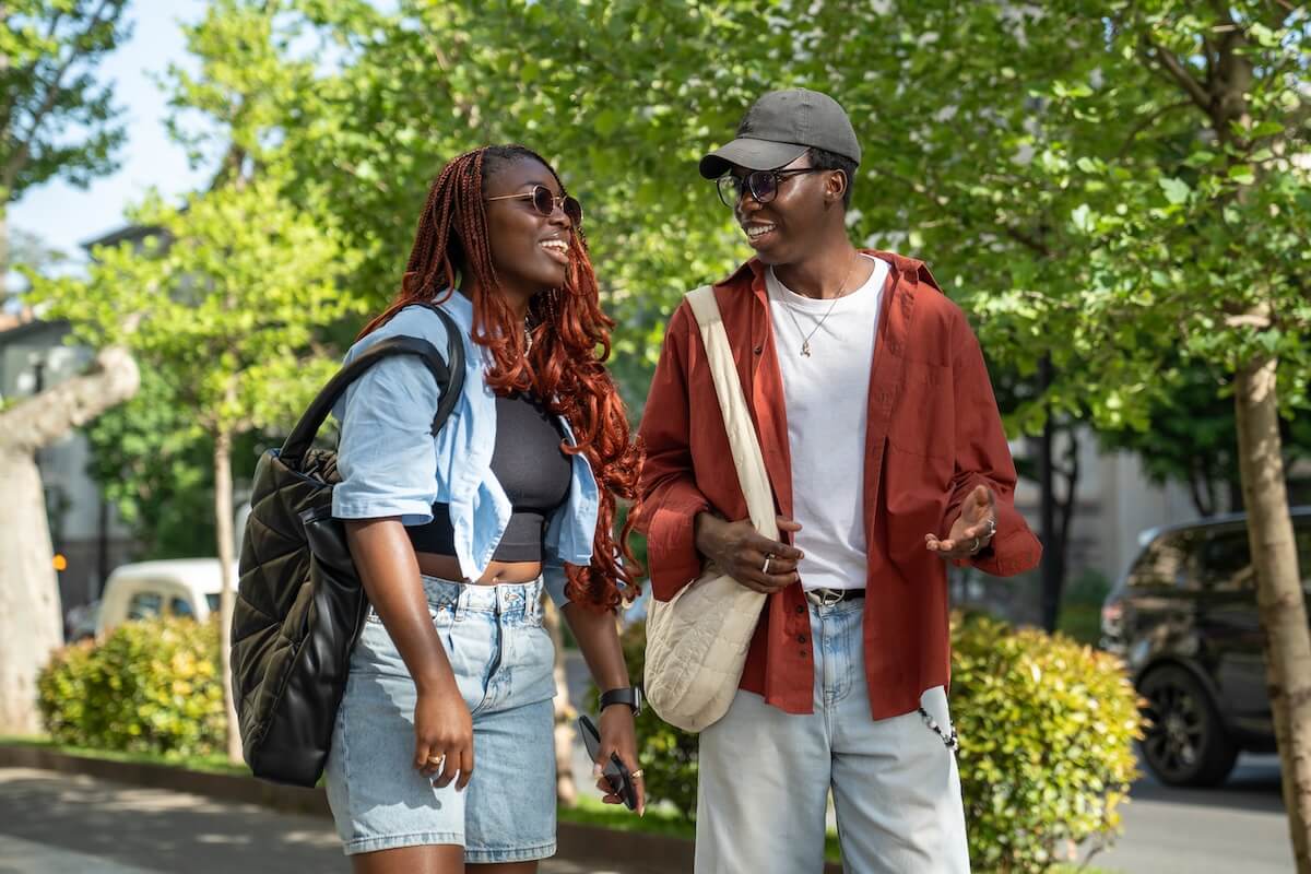 Shutterstock: Happy african american woman, man students walking down street together, enjoying each other's company. Joyful guy, girl couple of buddies communicating, talking, having funny amusing conversation.