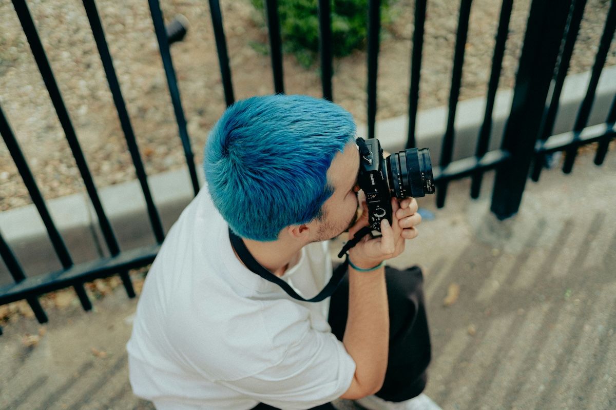 Unsplash: Man with blue hair taking photos by Braxton Apana