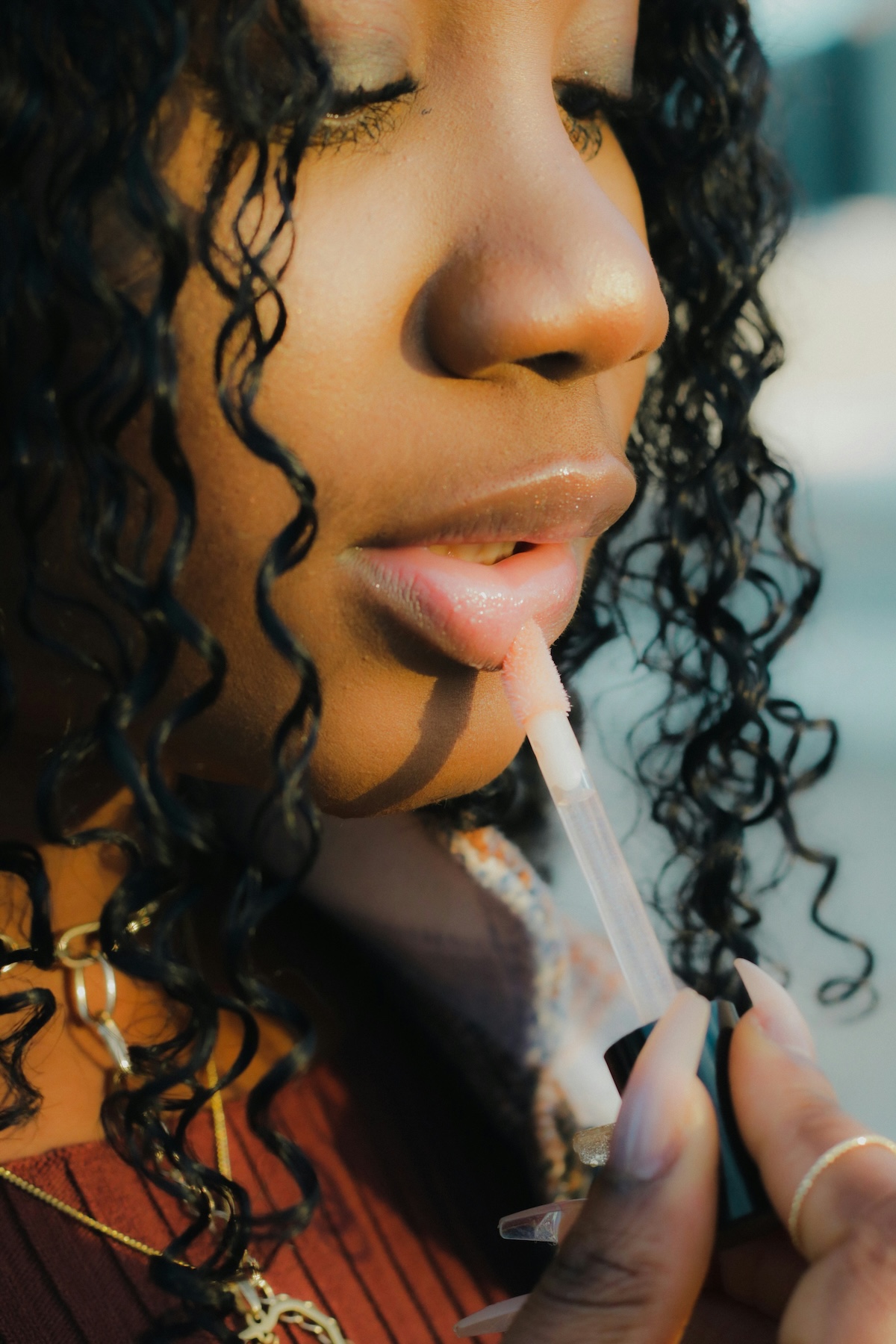 Unsplash: Woman applying lip gloss by Peter Kalonji
