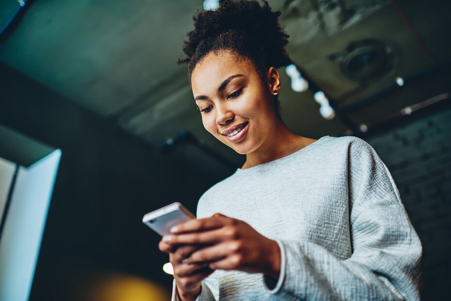 Shutterstock: Woman looking down at phone smiling and texting