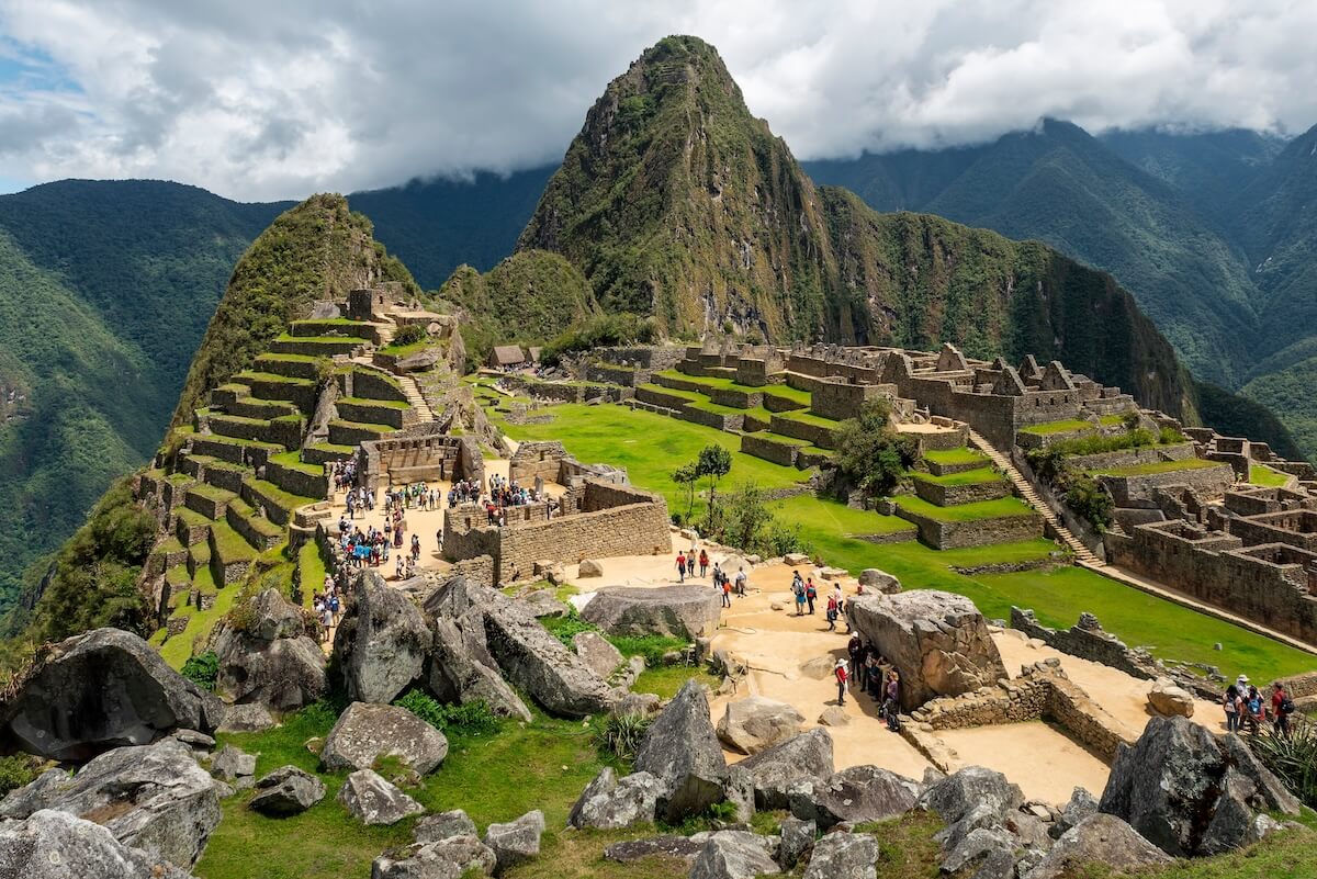 Shutterstock: Machu Picchu ruins with tourists with dramatic clouds, Machu Picchu historical Sanctuary, Cusco, Peru.