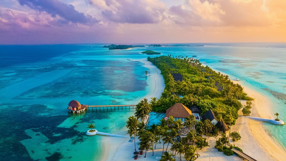 Shutterstock: Tropical paradise aerial view of a luxury island resort in the Maldives at sunset with turquoise lagoon, white sand beaches, lush palm trees and overwater villas.