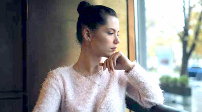 Shutterstock: a sad woman looking out a window