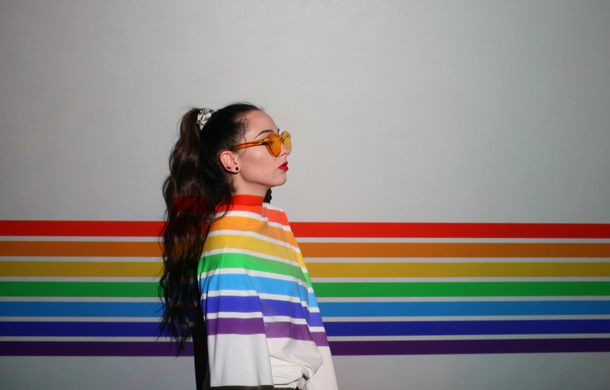 Unsplash: Woman with rainbow stripe shirt against wall by Isi Parente