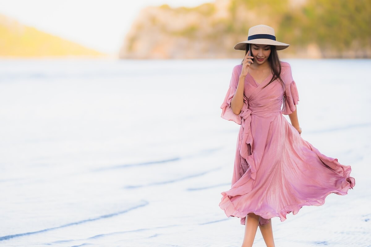 Shutterstock: Portrait young beautiful asian woman walk smile happy and talking mobile phone around the beach sea ocean for leisure travel in holiday vacation