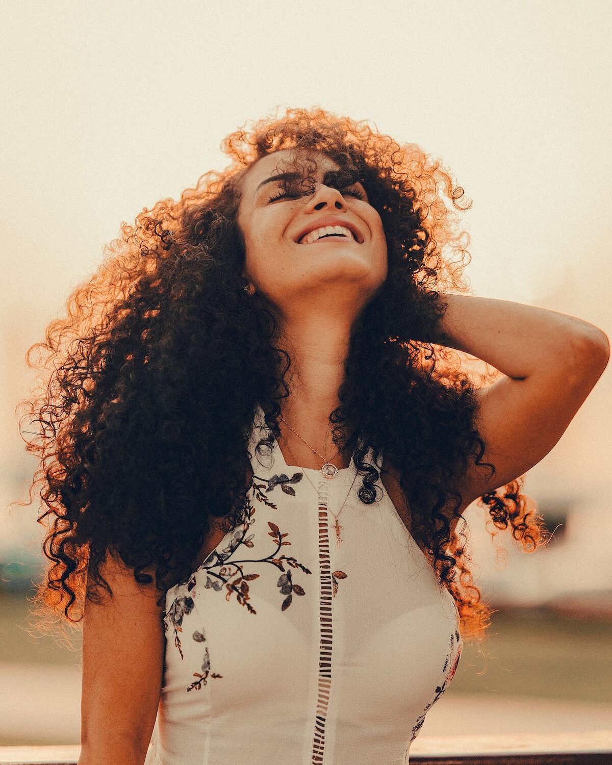 Unsplash: Smiling woman with curly hair looks up at the sky by Rameez Remy