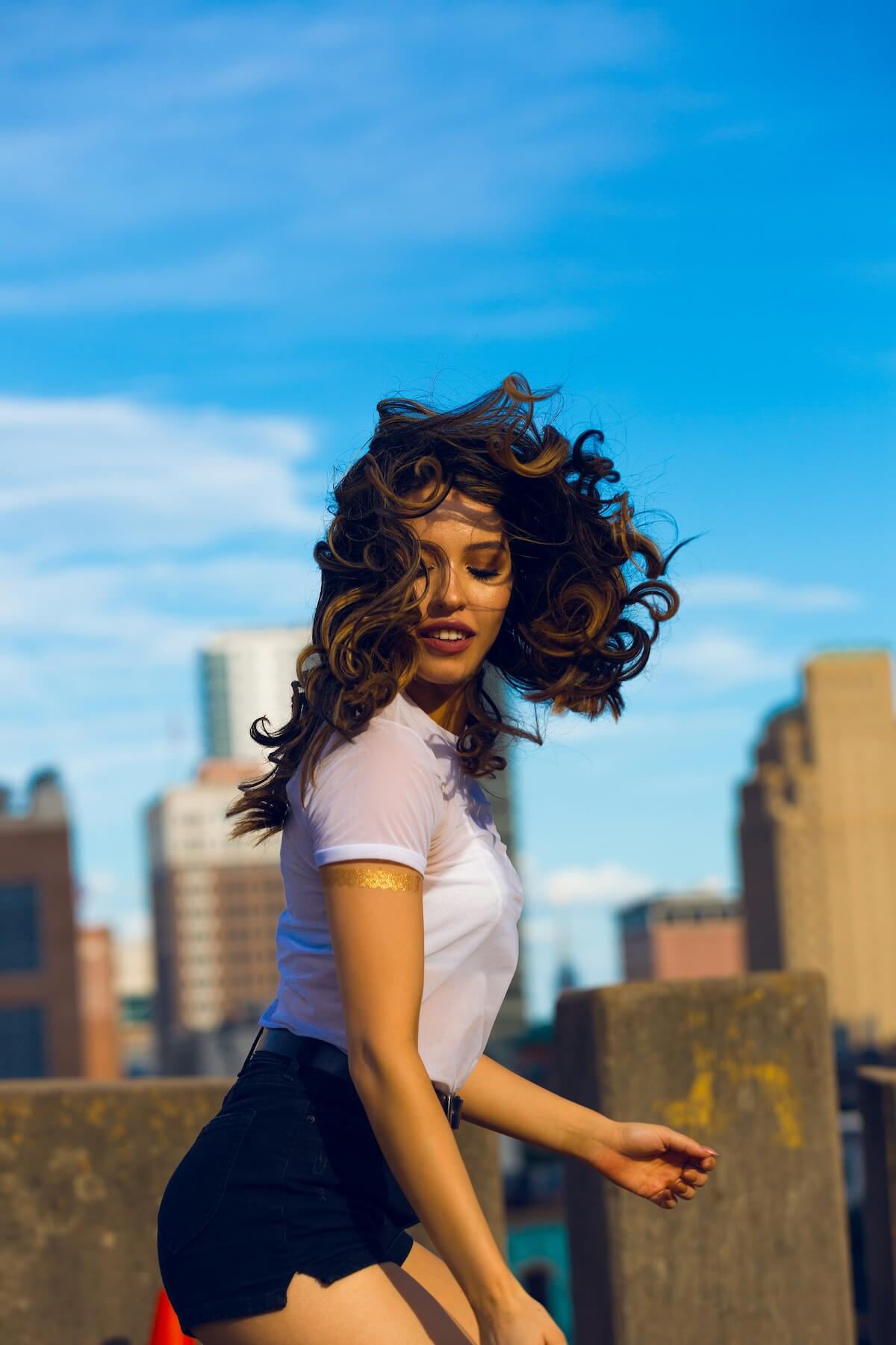 Unsplash: Woman with curly hair against city backdrop by Ayo Ogunseinde