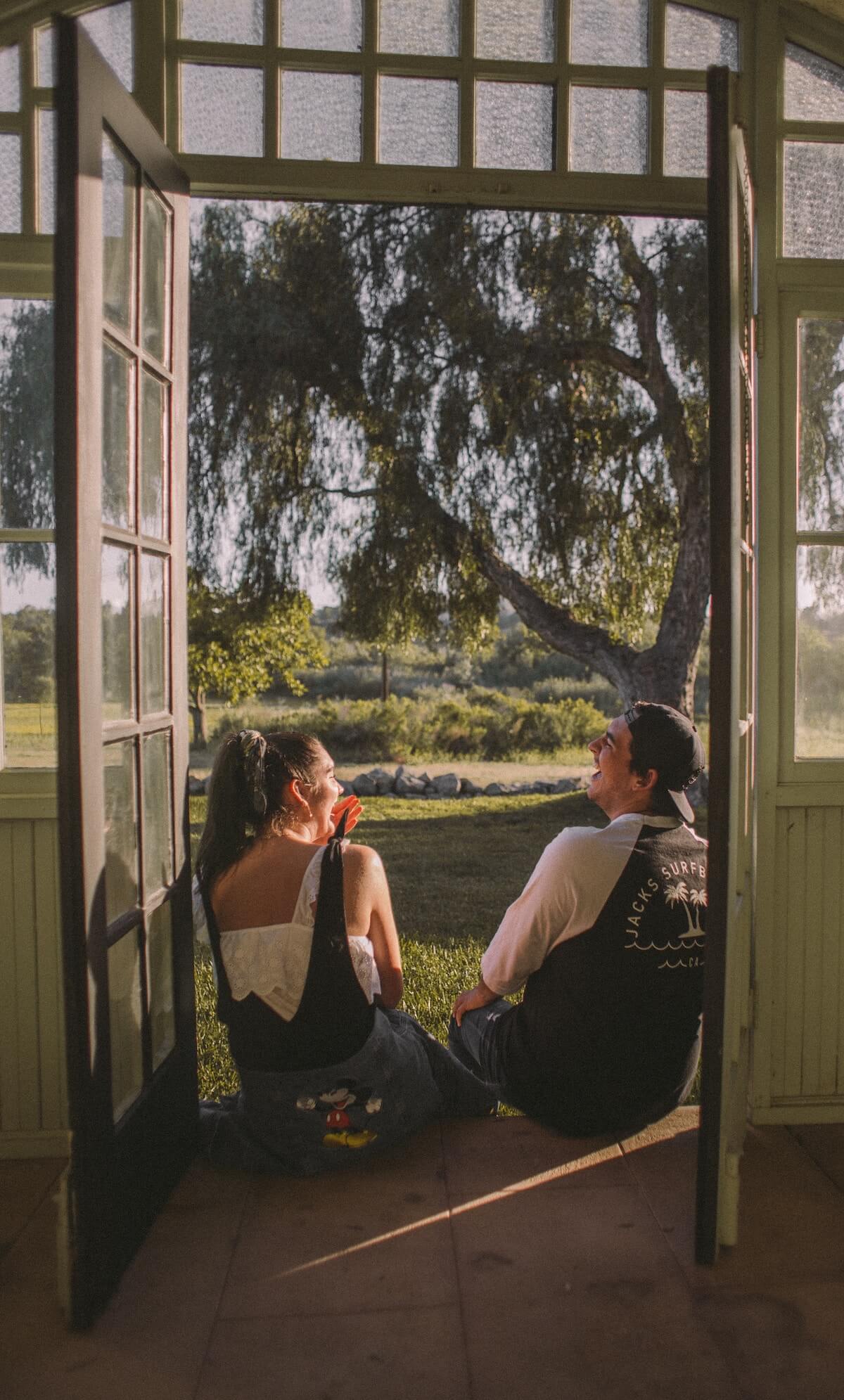 Unsplash Cute couple sitting in doorway laughing Jed Villejo