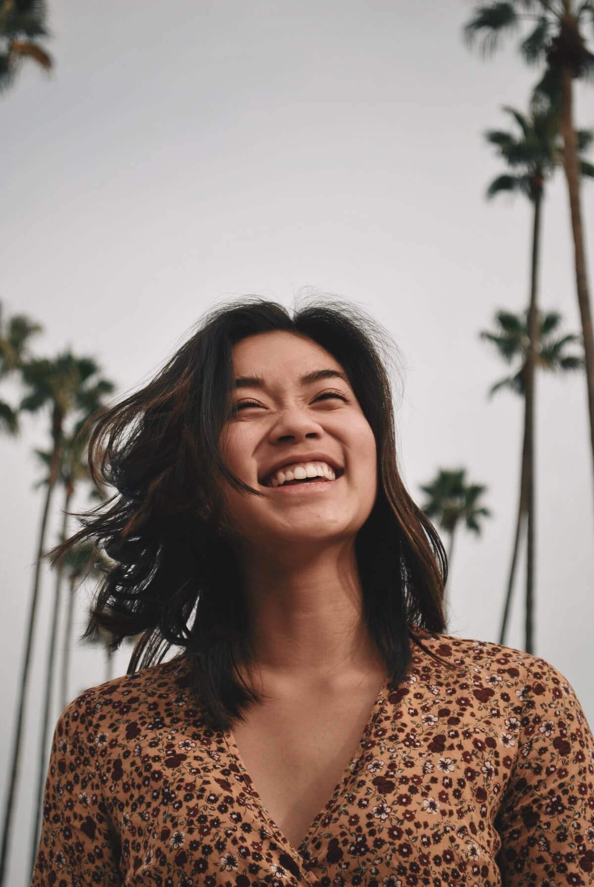Unsplash Woman smiling under palm trees Joel Mott