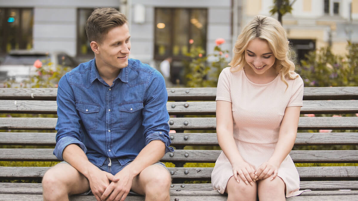 Shutterstock Shy blonde girl smiling, attractive guy flirting with beautiful woman on bench