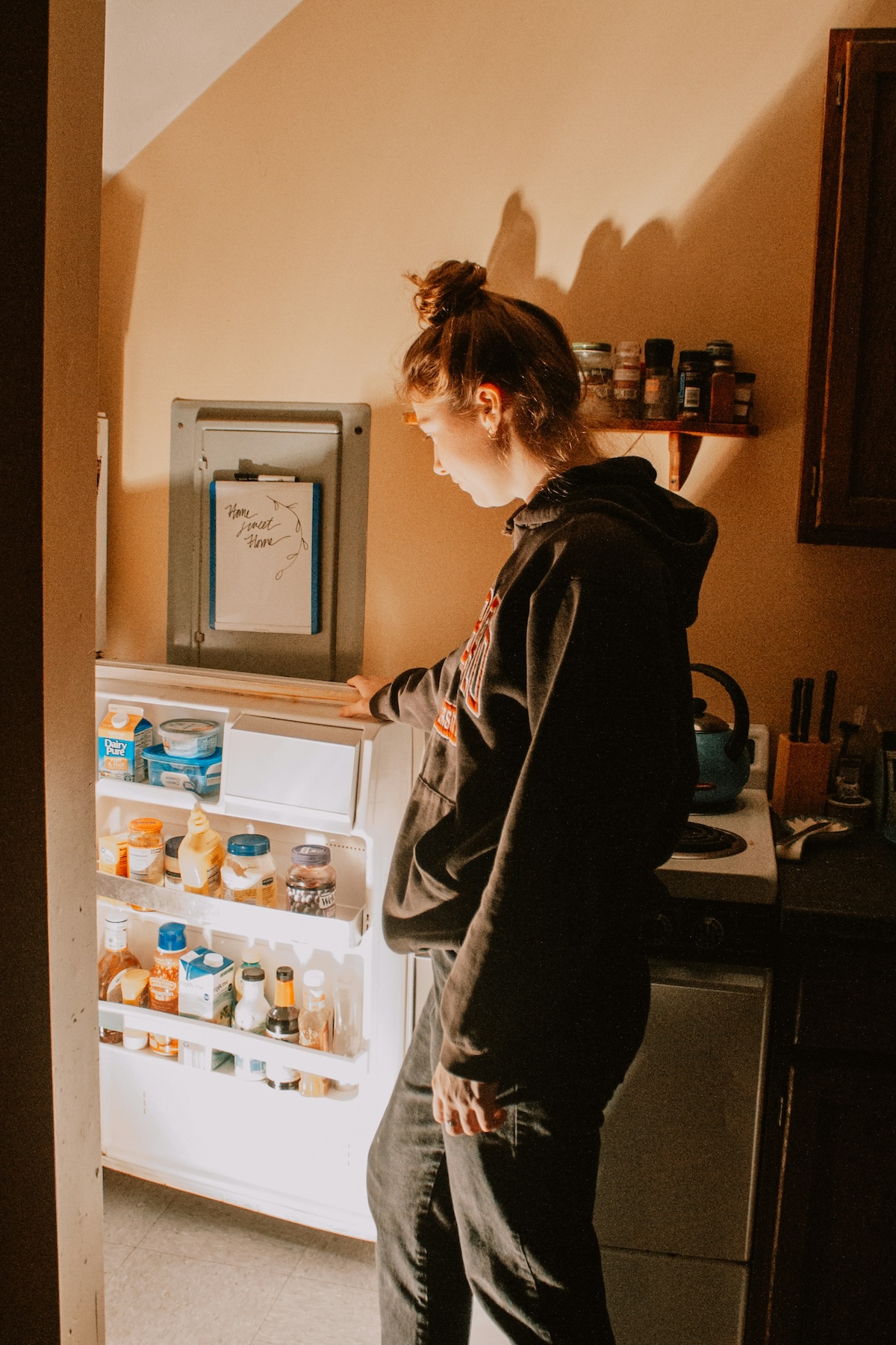 Unsplash: Woman looking down into fridge by Sydney Moore