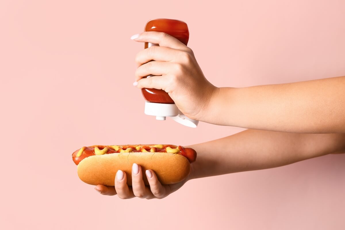 woman squirting ketchup on a hot dog